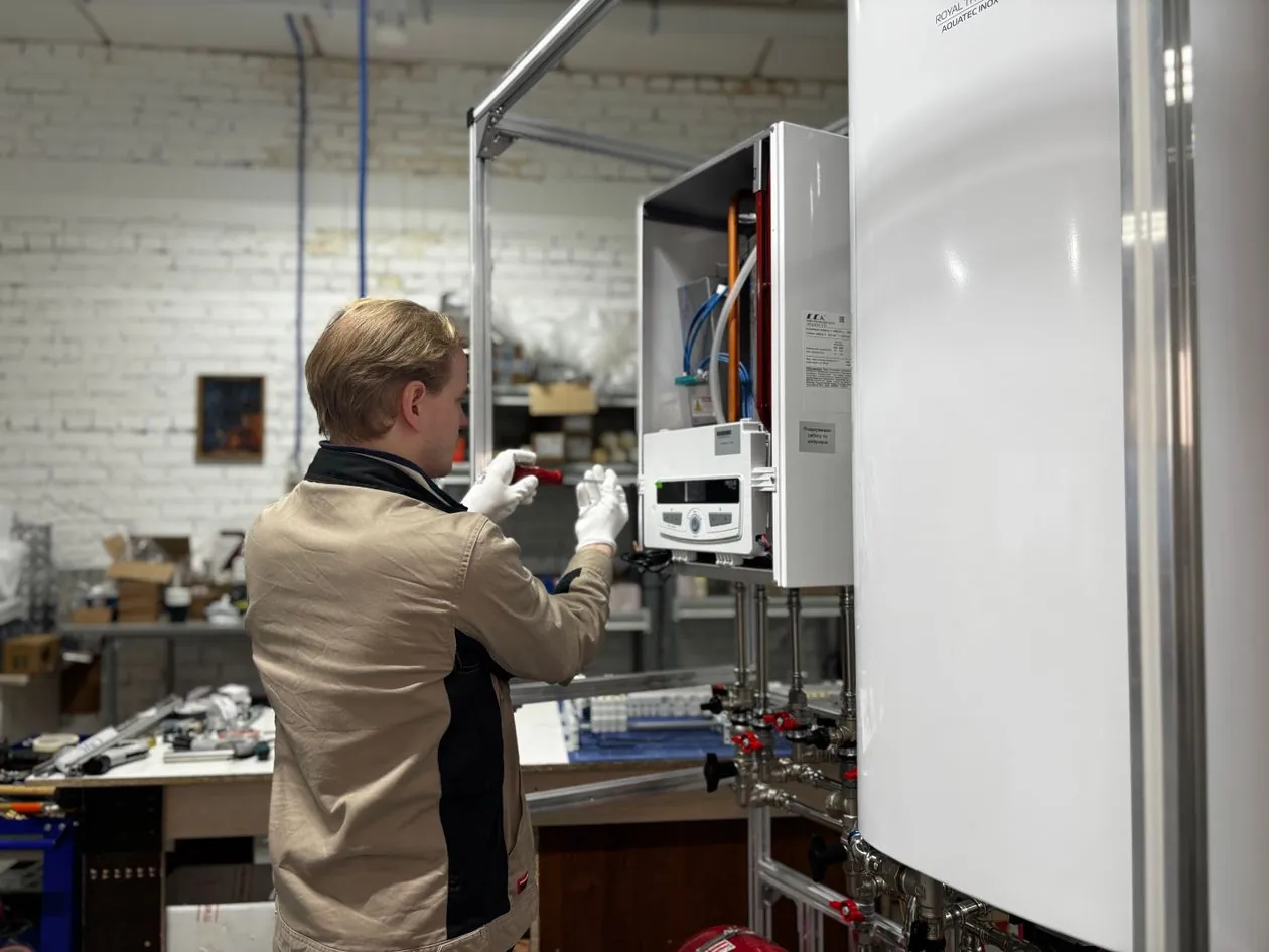 A heating technician working on a wall-mounted heating unit
